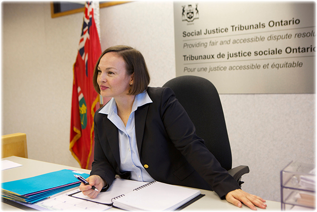 An adjudicator sits at a desk with a notebook.