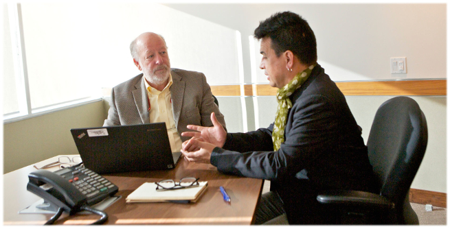 A man tells his story to an adjducator in a baordroom. The adjudicator listen.