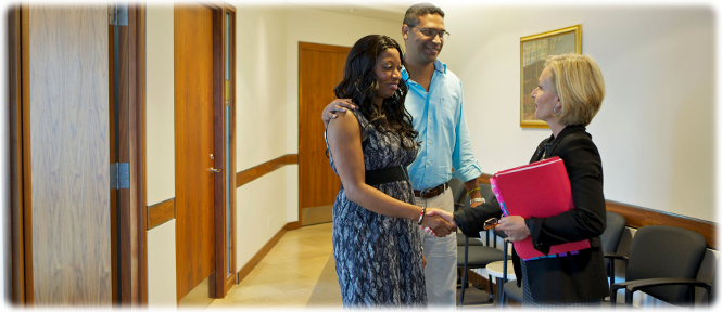 A couple in their thirties shake hands with an SJTO mediator in the hallway.