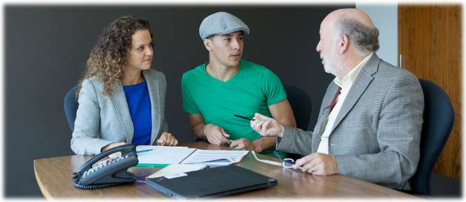 A young man and his female lawyer discuss documents with a male mediator in one of the tribunal's meeting rooms.